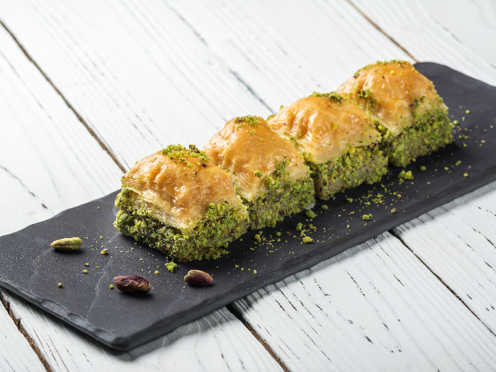 Turkish Baklava Turkish Delight, dulces orientales en un plato negro para servir en una mesa blanca de madera.