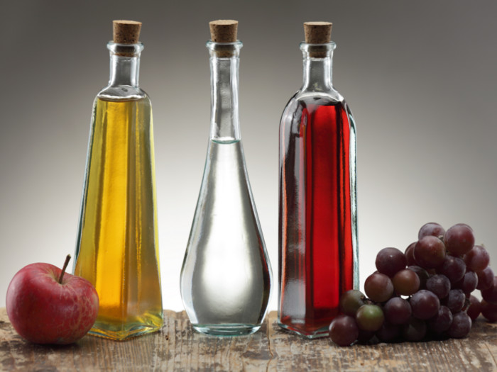Se colocan tres botellas de sustitutos balsámicos entre las uvas a la derecha y las manzanas a la izquierda.