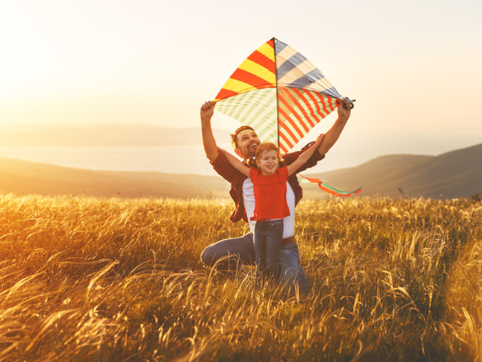 Padre e hijo volando cometas al aire libre luciendo felices y relajados