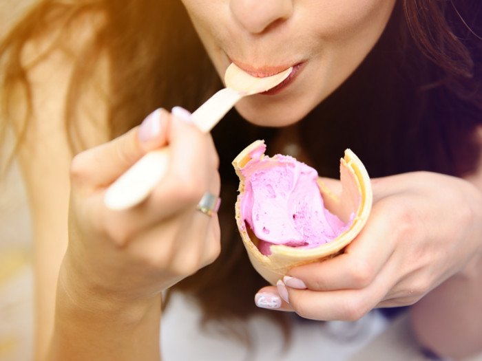 Primer plano de una mujer comiendo helado de un cono.