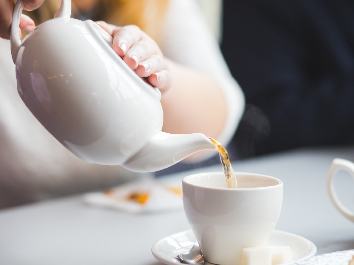 mujer sirviendo té en una taza de té