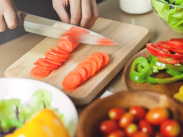 Una mujer corta zanahorias para la receta de zanahorias glaseadas
