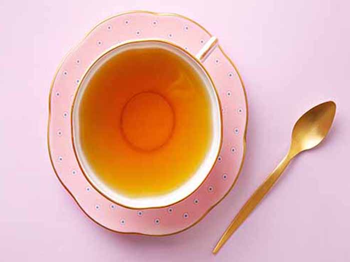 Vista plana de té en elegantes tazas y platillos con cucharas al lado