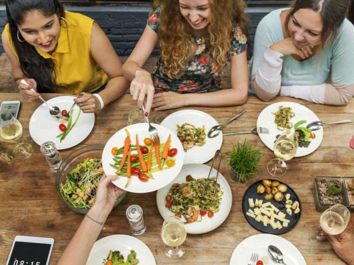 Personas sentadas alrededor de la mesa y compartiendo comida.