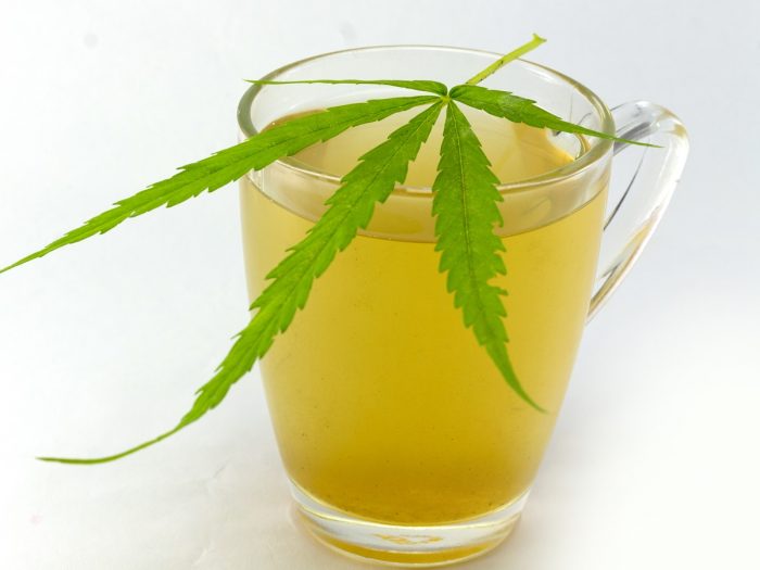 Una taza de té de cannabis con hojas frescas de cannabis