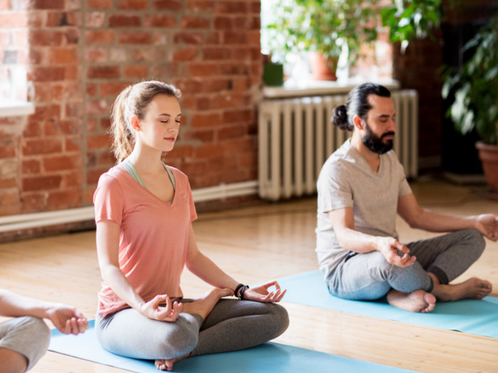 Un hombre y una mujer meditan en el interior.