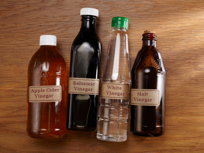 Cuatro botellas compuestas de diferentes tipos de vinagre.