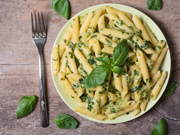 Pasta penne con pesto de espinacas y albahaca verde en un plato