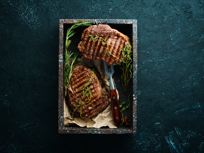 Rebanadas de bistec con romero y otras hierbas en plato negro